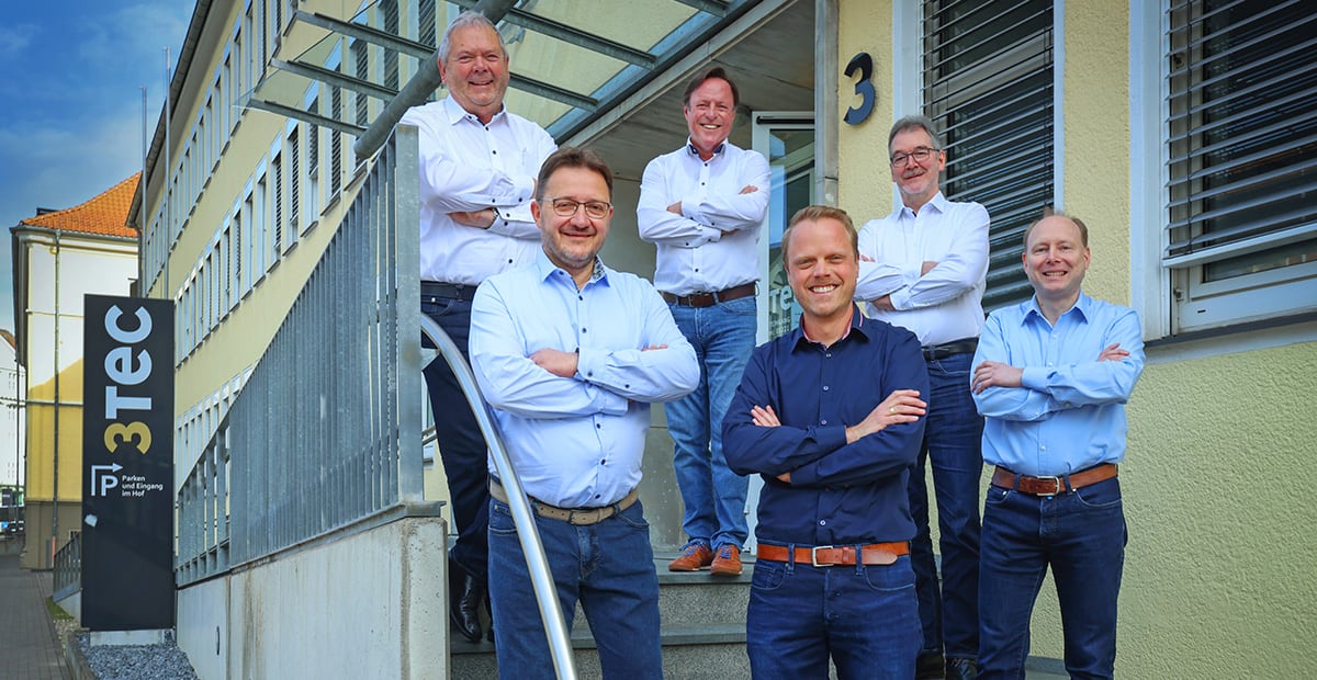 Sechs Männer stehen vor dem Gebäude von 3Tec, einem Unternehmen für Fertigungsleittechnik (MES).